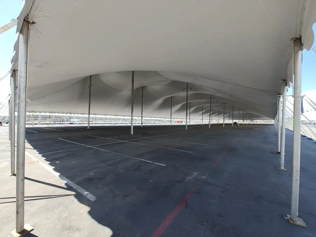 Interior view of a large 120ft wide tension tent set over an empty parking lot, showing unobstructed layout and center poles