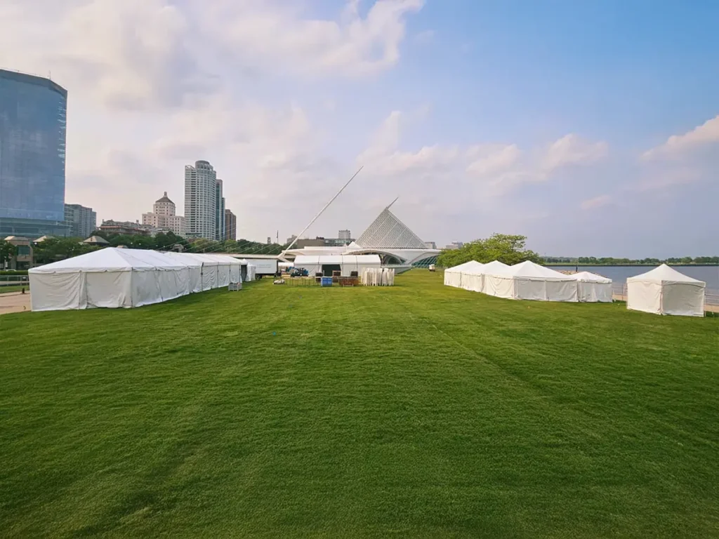 Multiple white Clearspan structures set up on a lawn along the lakefront with a city skyline in the background