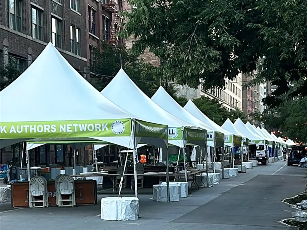 Row of high-peak frame tents lined along a city street for an outdoor market or event