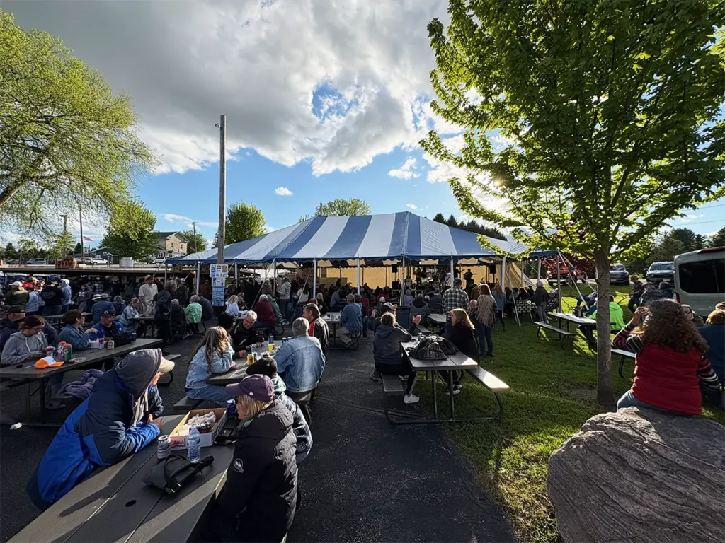 Blue and white striped festival tent surrounded by people eating and socializing outdoors