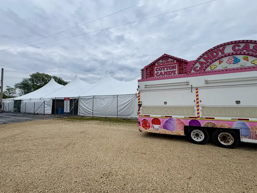 Tension tent setup at a county fair with high peaks and a cotton candy stand in the foreground