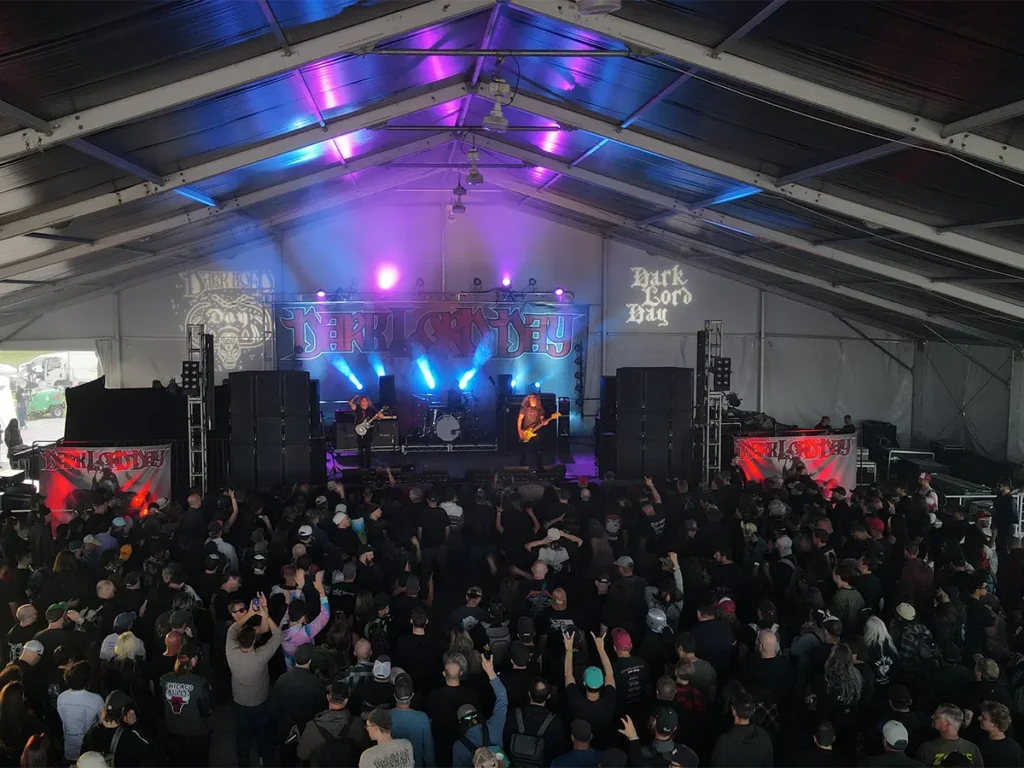 Rock band performing under the main stage tent with vibrant lighting and packed audience.