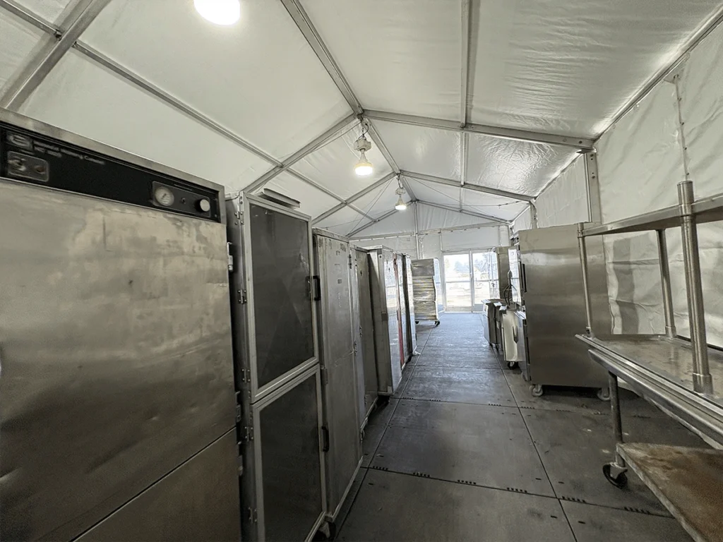 Interior of a functional catering tent filled with commercial kitchen equipment.