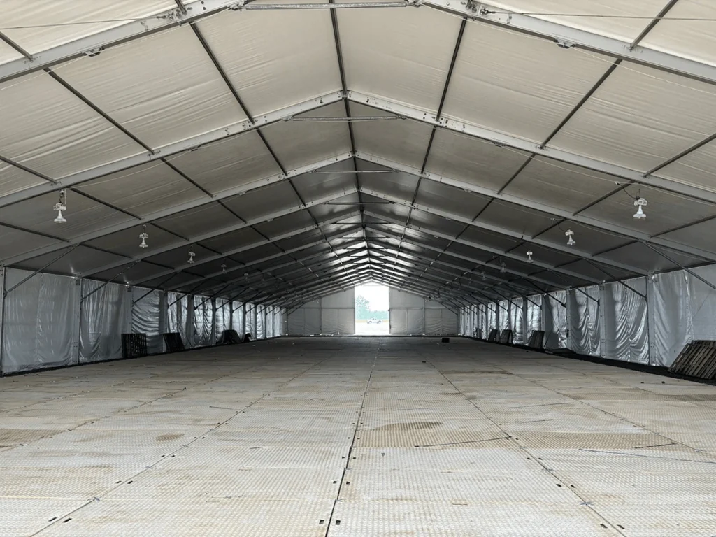 Wide interior view of a clearspan structure with hard flooring and ceiling lights.