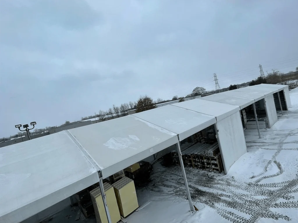 Clearspan tents in snow-covered yard used for storing materials and equipment