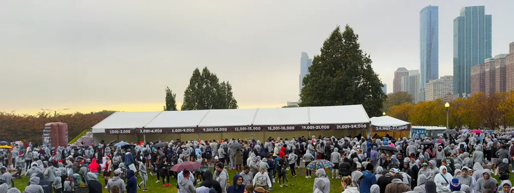 Thousands of runners gather in Grant Park in front of numbered corrals under white tents before the Hot Chocolate Chicago race.
