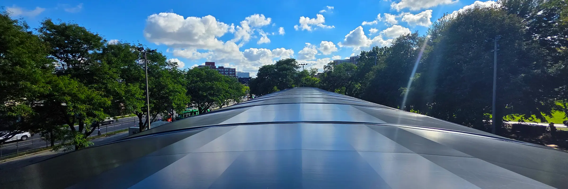 Wide panoramic shot along the full black roof of a clearspan festival structure at ARC Music Festival, with trees and clouds on both sides.
