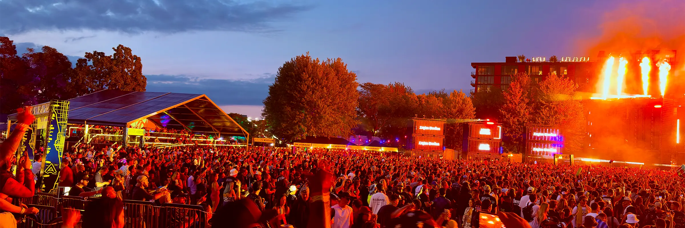 Panoramic night view of the ARC Music Festival main stage with a packed crowd, lighting towers and pyrotechnics across the field.