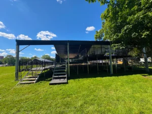 Crowd and main stage seen from under a VIP clearspan deck at ARC, with guests watching from behind railings.
