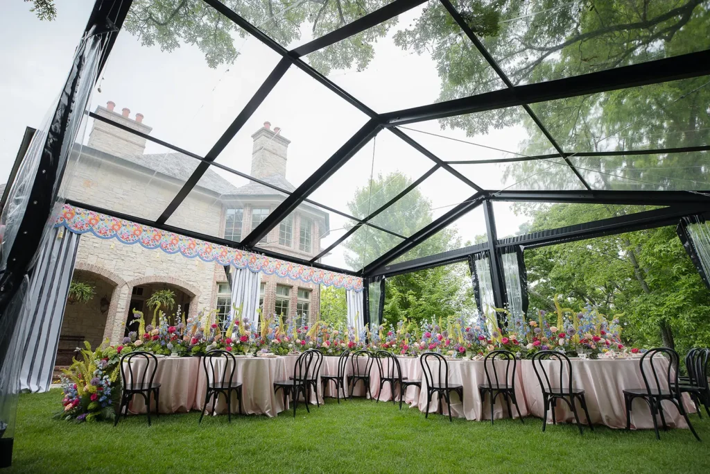 Overhead perspective of a clear-roof tent showing pastel floral installations and round dining tables.
