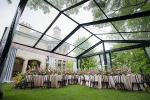 Overhead perspective of a clear-roof tent showing pastel floral installations and round dining tables.