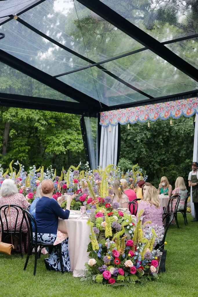 Long view of guests seated at floral-filled tables beneath a clearspan tent.