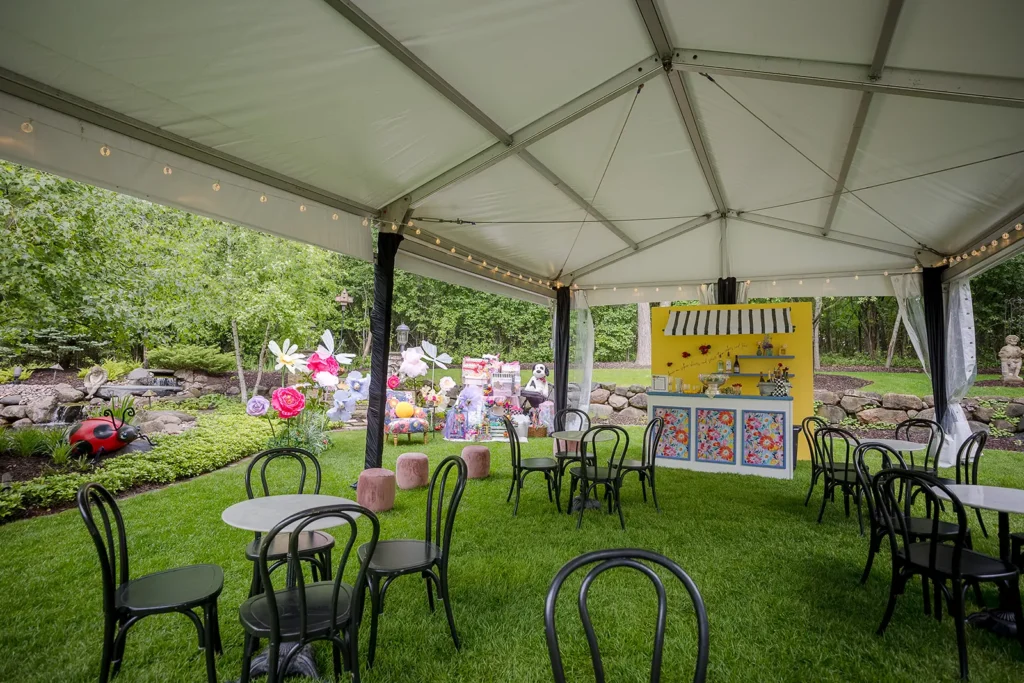 clearspan tent lounge area with café tables, floral props, and a custom bar setup in a landscaped garden.