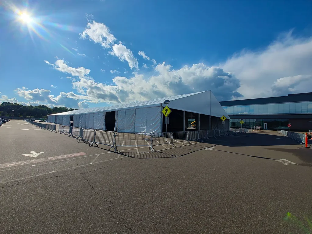 Wide exterior view of a long clearspan tent installation with barricades at Boston Scientific.