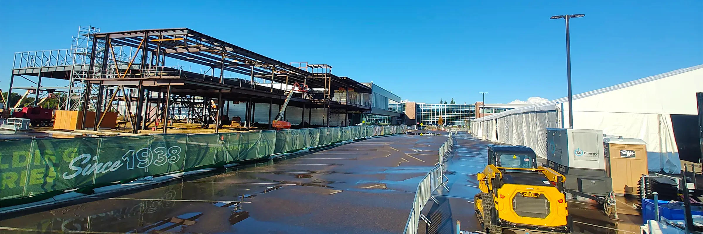 Construction site with steel framing beside a long clearspan structure used for Boston Scientific operations.
