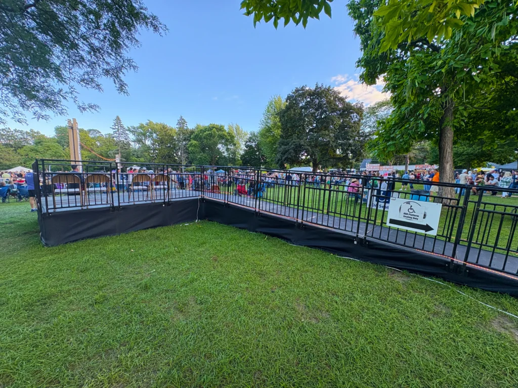 ADA-accessible viewing platform with a ramp and safety railings located near the festival crowd.