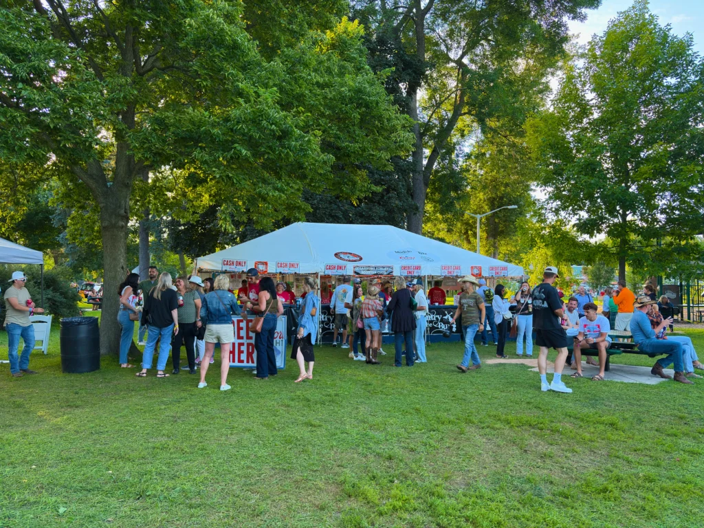 Guests gathered around a beer tent under a white frame tent at Country in the Burg.