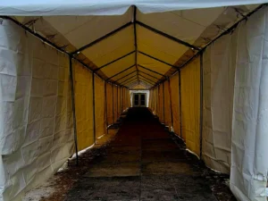 Covered walkway inside an a-frame clearspan structure with enclosed vinyl sidewalls during a winter event setup.