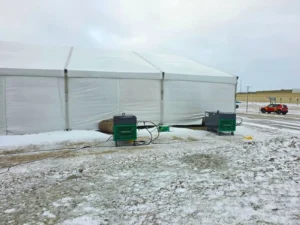 End wall of an a-frame clearspan structure with enclosed vinyl panels during a winter installation.