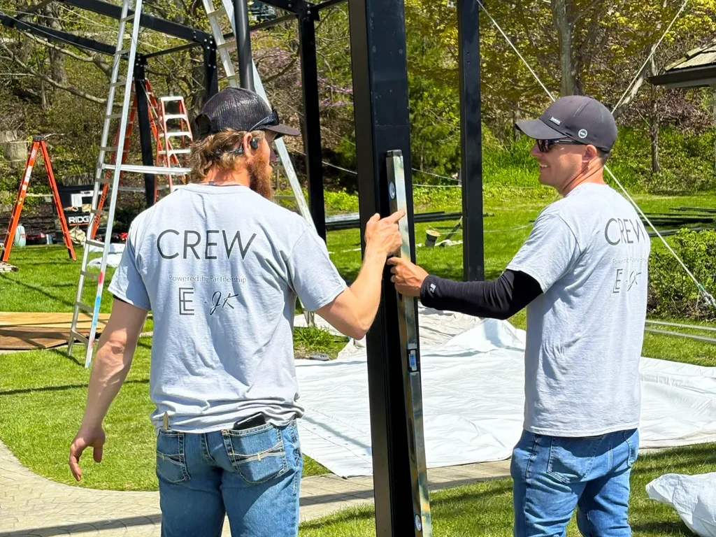 Two crew members level and align Levo clearspan frame components during a waterfront wedding install in Oconomowoc, Wisconsin.