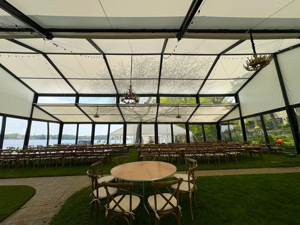 Wide interior view of the Levo clearspan wedding structure with seating and tables set on the lawn, framed by clear walls and lake views.