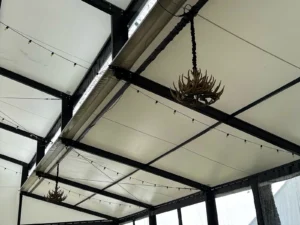 Overhead detail of Napa string lights and a large chandelier rigged to the rafters inside a Levo clearspan wedding structure.