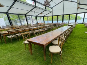 Reception tables arranged inside a Levo clearspan structure with clear wall panels and lake views during a wedding setup in Oconomowoc, Wisconsin.