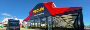 Mecum Auctions “The Barn” branded clearspan structure with a glass front entrance and classic cars inside.