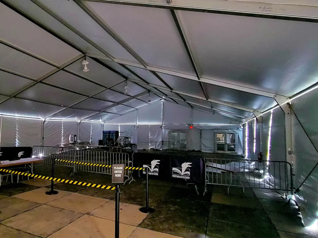 Event entry area inside a clearspan tent at the Pettit National Ice Center with crowd control fencing and check-in stations.